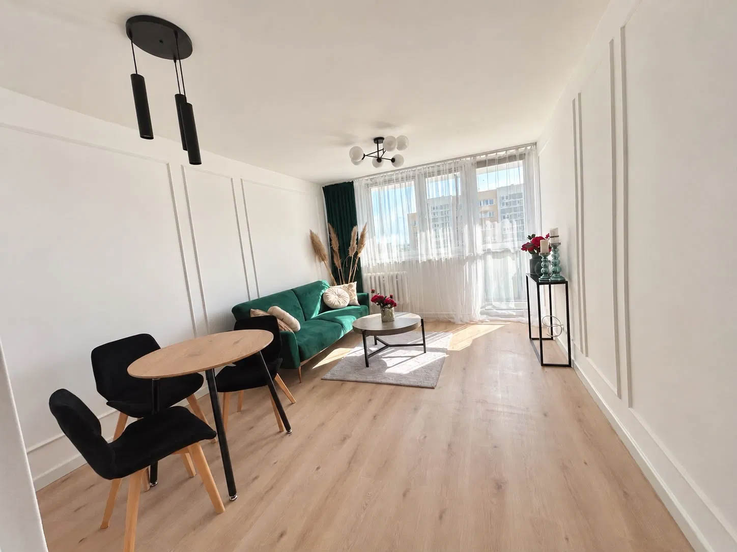 Jasny salon z zieloną kanapą, stołem i krzesłami w mieszkaniu na sprzedaż w Opolu
