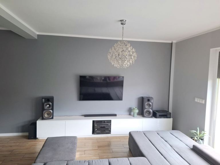 Nowoczesny salon w apartamencie na sprzedaż w Opolu z szarą ścianą i dużym telewizorem
