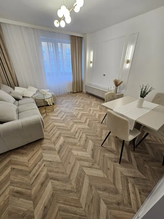 Jasny salon w mieszkaniu na sprzedaż w Opolu z dużym oknem, szarą kanapą i jadalnią