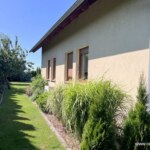 Widok na otynkowaną elewację wolnostojącego domu i zagospodarowany ogród w Opolu Czarnowąsach