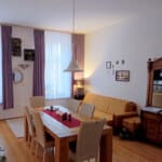Przestronny salon z dużym stołem jadalnianym, sofą i wysokimi oknami w mieszkaniu w Opolu