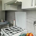 Biała kuchnia w mieszkaniu na sprzedaż w Prudniku z kuchenką gazową, okapem i zlewem