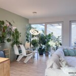 Jasny salon w domu w Chmielowicach z dużą ilością roślin doniczkowych i dużymi przeszkleniami wychodzącymi na taras