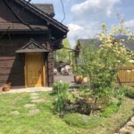 widok z zewnątrz na drewniany dom w Szczyrku z zielonym ogrodem i tarasem