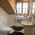 Łazienka na poddaszu w domu w Szczyrku z drewnianym wykończeniem ścian oraz białą ceramiką sanitarną