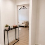 Jasny przedpokój w mieszkaniu w Opolu z czarną konsolą i widokiem na salon