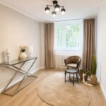 Jasny salon w mieszkaniu na sprzedaż w Opolu z oknem, szarym fotele i szklaną konsolą