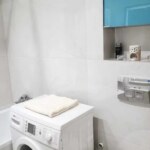 Jasna łazienka w mieszkaniu na sprzedaż w Opolu z pralką i niebieską szafką