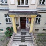 Wejście do kamienicy w Opolu na Pasiece z ozdobnymi kolumnami i schodami prowadzącymi do drzwi