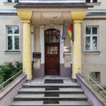 Wejście do zabytkowej kamienicy w Opolu na Pasiece z ozdobnymi kolumnami i drewnianymi drzwiami