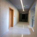 Nowoczesny korytarz w budynku mieszkalnym w Opolu z jasną podłogą i drzwiami wejściowymi do apartamentu