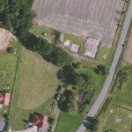 Widok z góry na działkę budowlaną z zielenią i przylegającą do niej drogą dojazdową