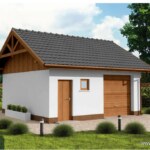 Wolnostojacy budynek gospodarczy z bialymi scianami, brazowa brama garażowa oraz ciemnym dachem dachówkowym w otoczeniu zieleni